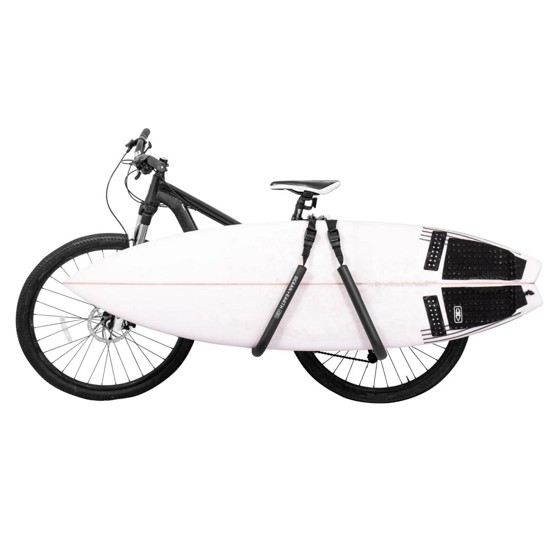 A surfboard rack mounted on a bicycle, with a white surfboard secured in a protective padded case on the back of the bike.